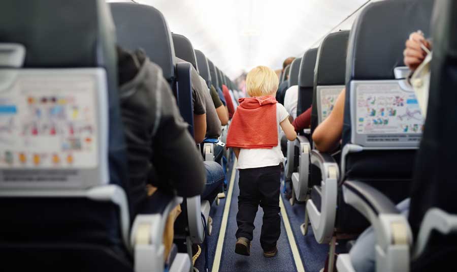 A little boy walking on the airplane aisle