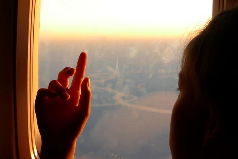 child's hand on window of plane