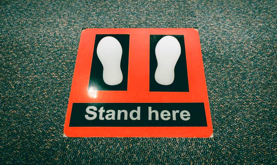 A stand here sign on a floor in an airport