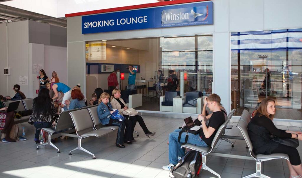 Passengers waiting outside the smoking lounge on an airport, wondering "can you take a lighter on a plane?"